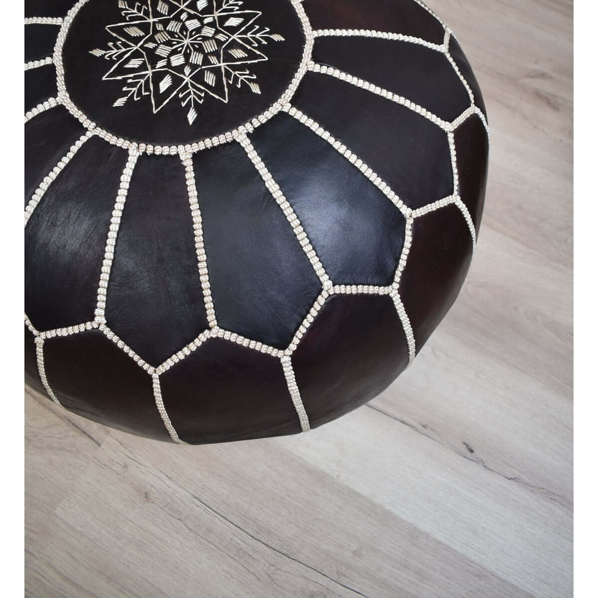 Donkerbruine Marokkaanse leren poef met decoratief stiksel, ideaal als voetenbankje of zitplaats in huis.