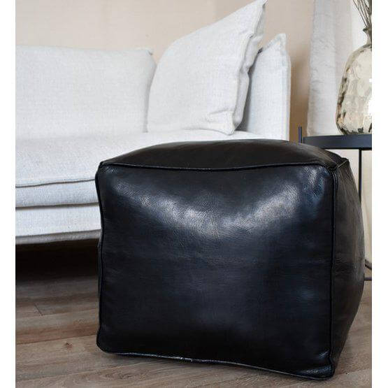 Zwarte leren vierkante poef, handgemaakt en multifunctioneel, perfect als voetenbankje of extra zitplaats, in een gezellige boho-sfeer woonkamer.