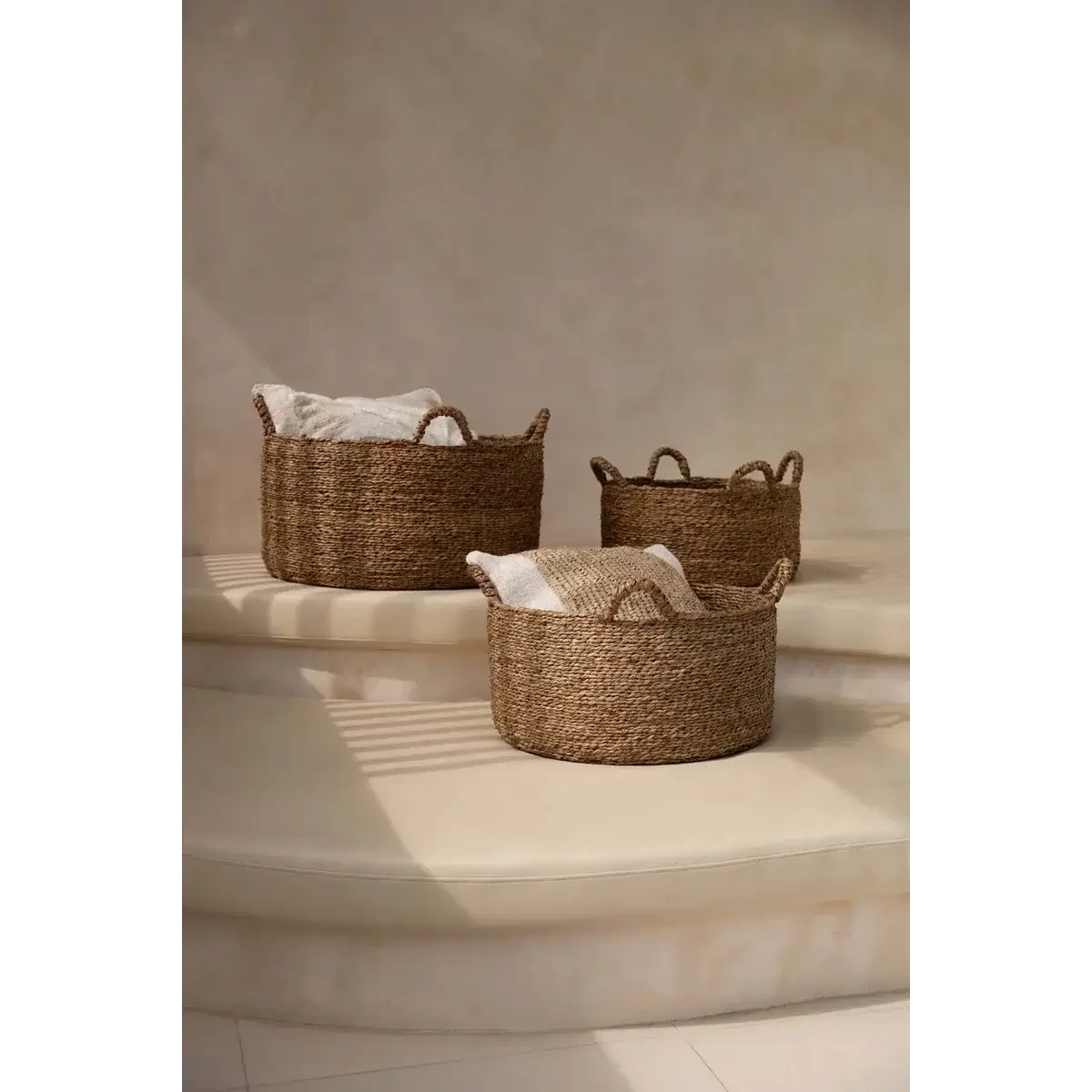 Stylish sea-grass woven baskets with four handles, perfect for laundry, towels, or toy storage in modern or boho chic interiors.