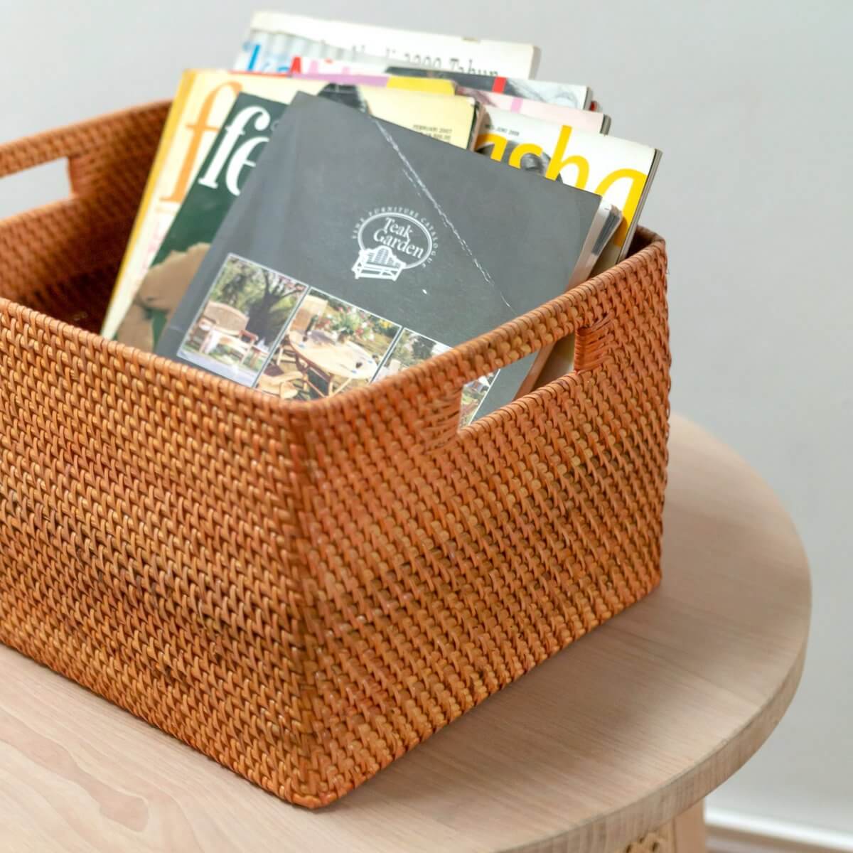 Decoratieve Warsa rotan opbergmand gevuld met tijdschriften op een houten tafel. Ideaal voor stijlvolle opslag en duurzaamheid.