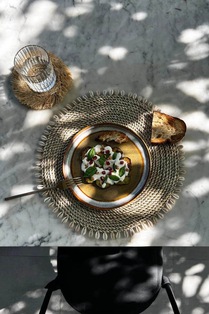 Lunchtafel met zeegras placemat, glas en smakelijke lunch op een zonnige dag.