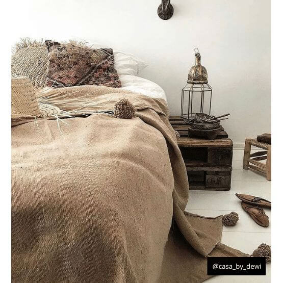 Gezellige Marokkaanse pompompdeken in beige kleur toont rustieke elegantie in slaapkamer, perfect voor moderne en bohemien woonstijlen.