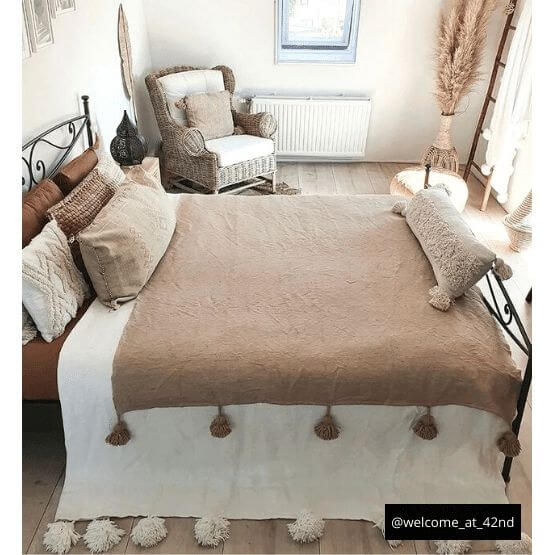 Gezellig beige Marokkaanse pompondeken op bed in stijlvolle slaapkamer, perfect voor elk interieur. Prachtig en knus!