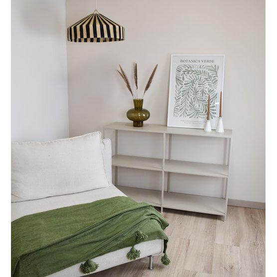Groene Marokkaanse pompomdeken op een bed, met moderne bohemien inrichting.