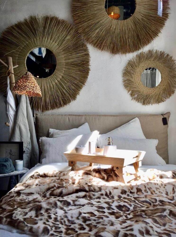 Ronde rotan spiegel lux aan de muur in boho slaapkamer; handgemaakte decoratie voor meer sfeer en diepte.