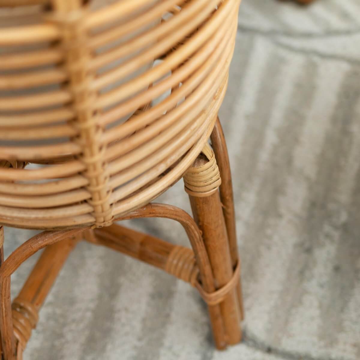 Close-up van een rotan plantenstandaard, natuurlijke boho-stijl, perfect voor plantenpotten tot Ø20 cm, Akara ontwerp.