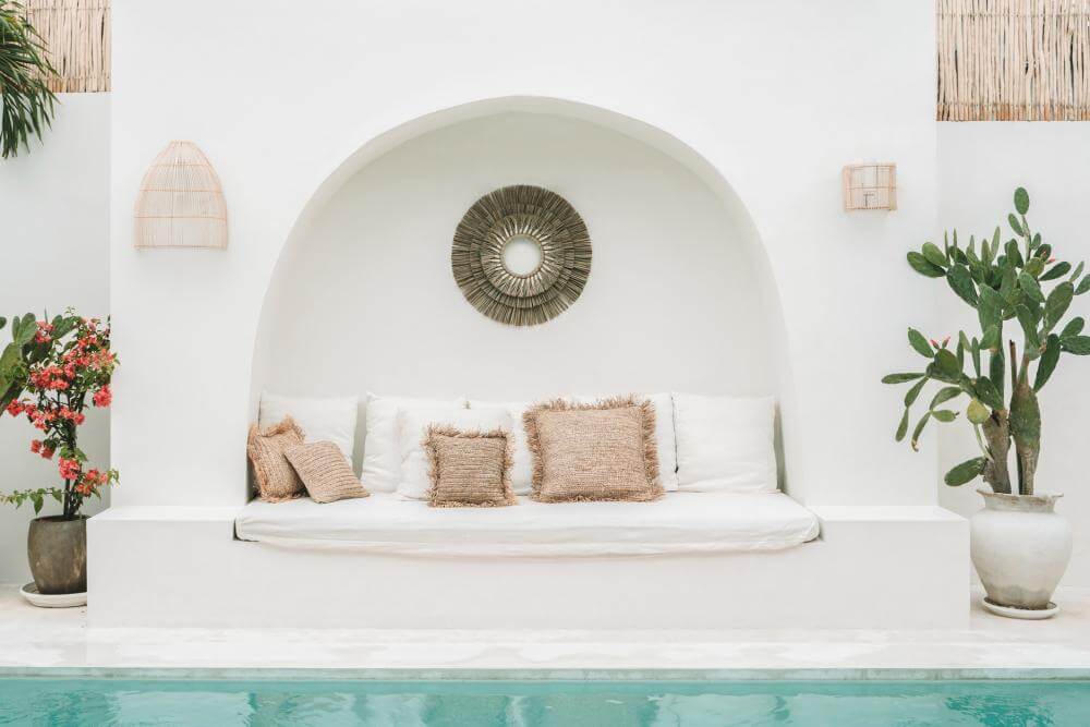 Alt Tag: Gezellig terras met rotan wandlamp en comfortabele kussens bij een zwembad, perfecte plek voor ontspanning en sfeer.