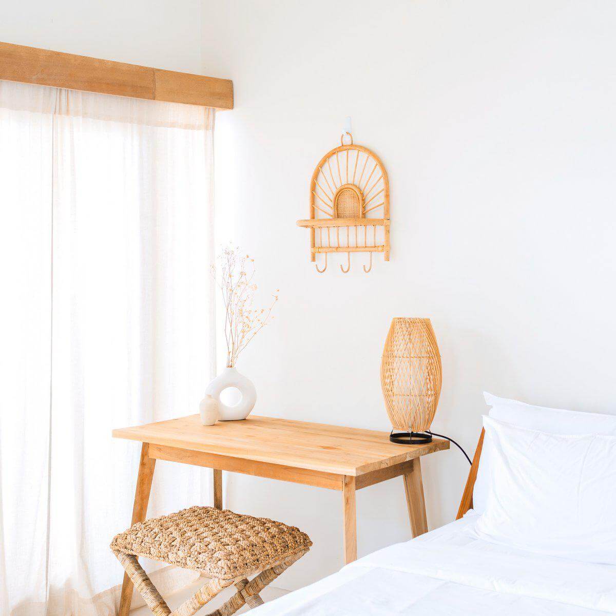 Kleine rotan wandplank Banten als boho-decor, met haakjes, zonnepatroon en natuurlijke materialen in een lichte kamer.