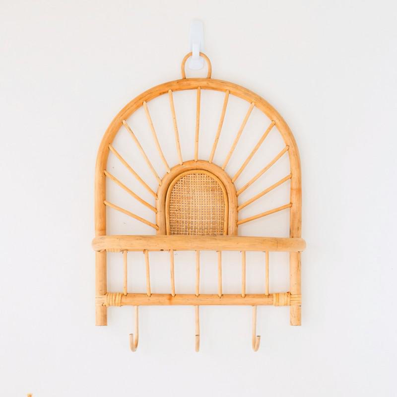 Rotan wandplank met boho-charme en haken tegen witte achtergrond, ideaal voor stijlvolle muurdecoratie en organisatie.