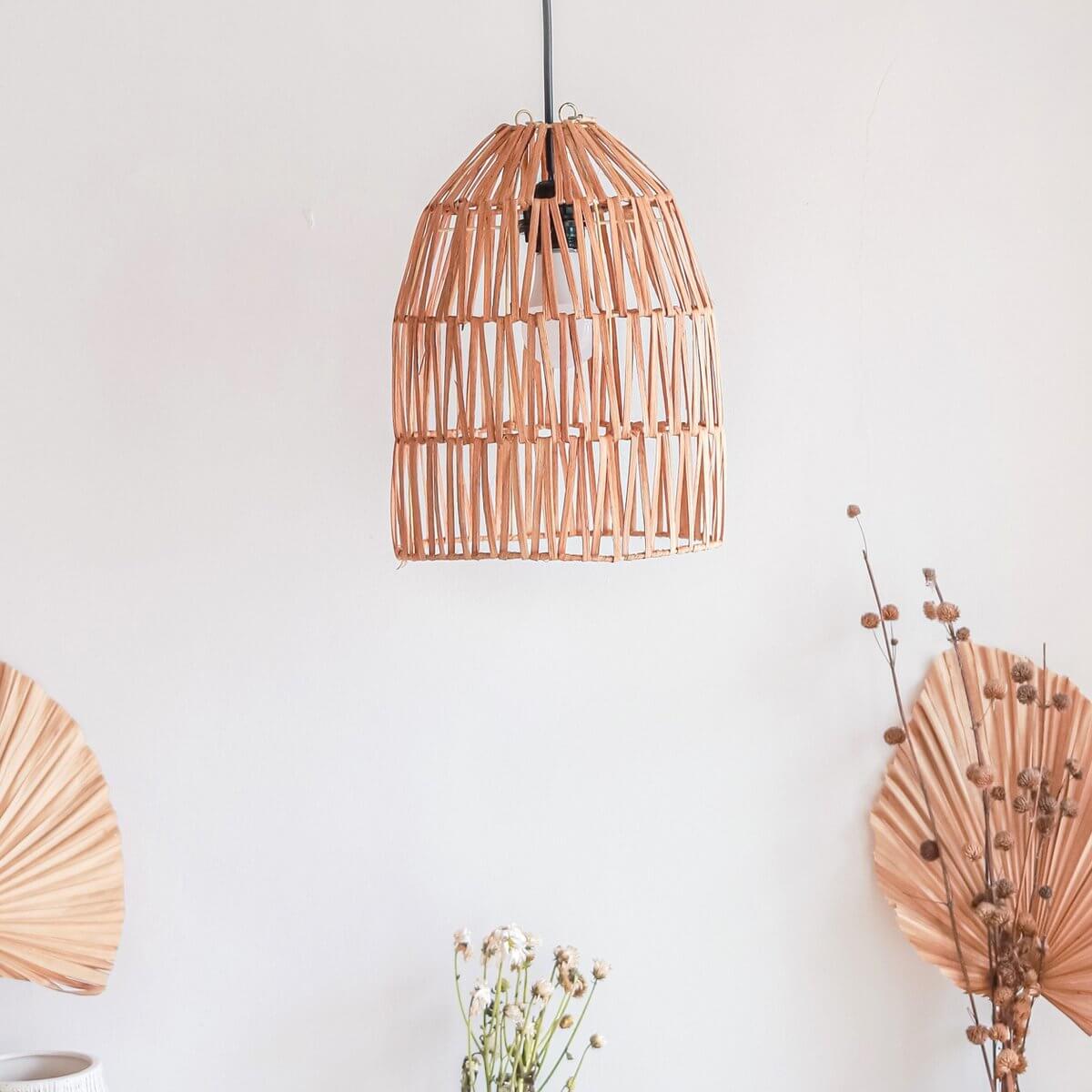 Rotan hanglamp MALUKA in natuurlijke setting met boho-stijl decor, perfect voor een rustgevende, warme uitstraling in je interieur.