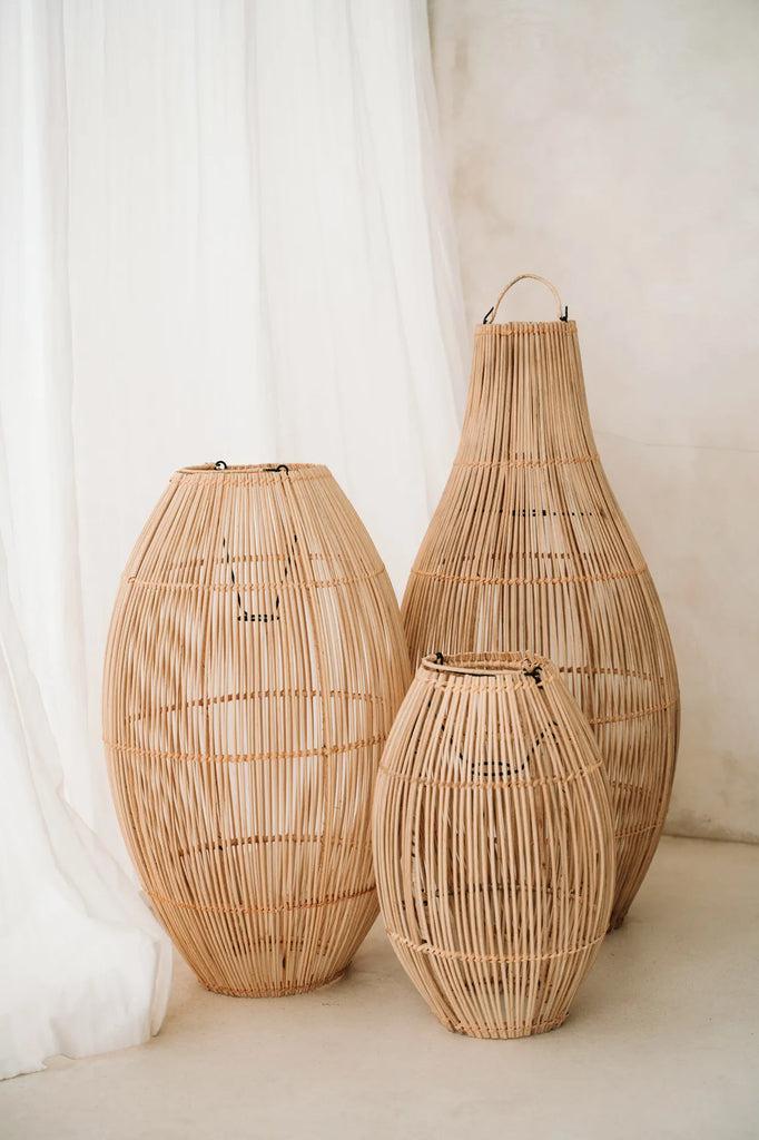 Drie rotan hanglampen The Zuri in klokvorm, ideaal voor sfeervolle verlichting in huis of overdekte buitenruimte.