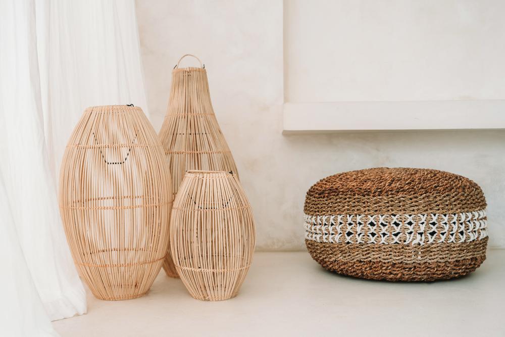 Rotan hanglampen The Zuri in drie maten naast een gevlochten poef voor een sfeervolle, moderne inrichting. Perfect voor binnen of buiten.