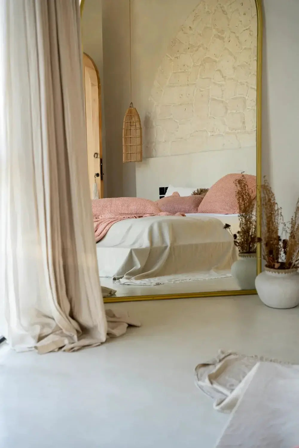 Boho slaapkamer met rotan lamp The Fish Trap en spiegel voor een sfeervol interieur.