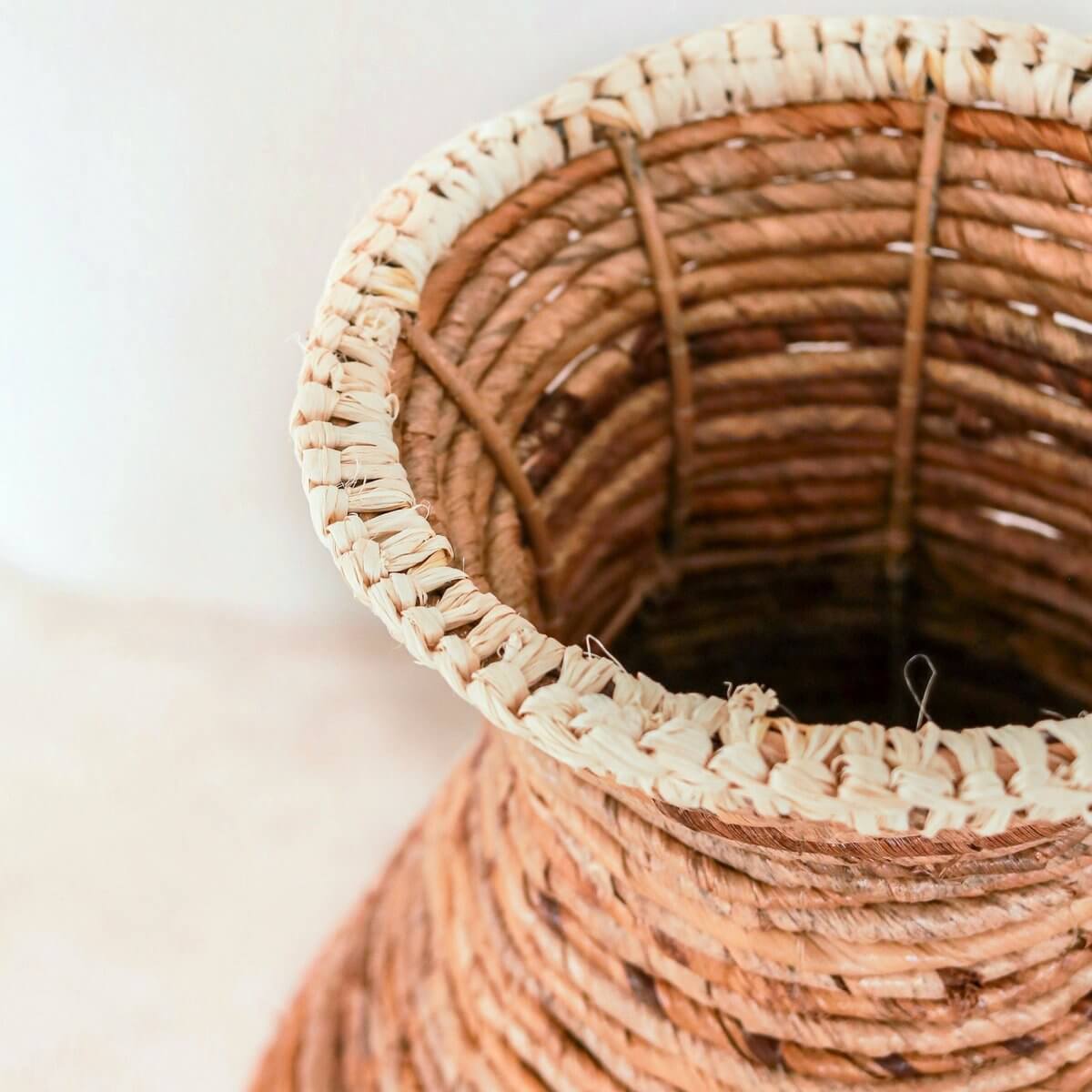 Handgevlochten vaas van robuust natuurlijk materiaal, elegant ontworpen met lichte raffia accenten, perfect voor een stijlvolle inrichting.