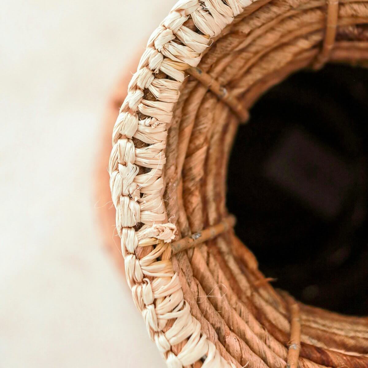 Bovenaanzicht van handgemaakte vaas gemaakt van robuuste bananenvezels en gevlochten raffia, vervaardigd in een familiebedrijf.