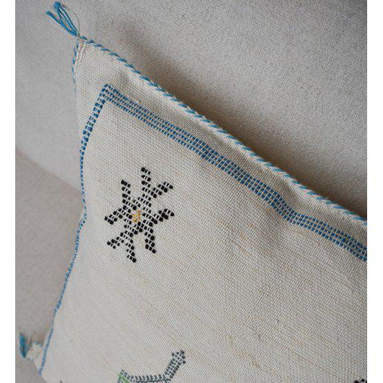 Bohemian Sabra kussen in zandkleur met blauwe accenten en rustgevende patronen, perfect voor een Ibiza sfeer in huis of tuin.