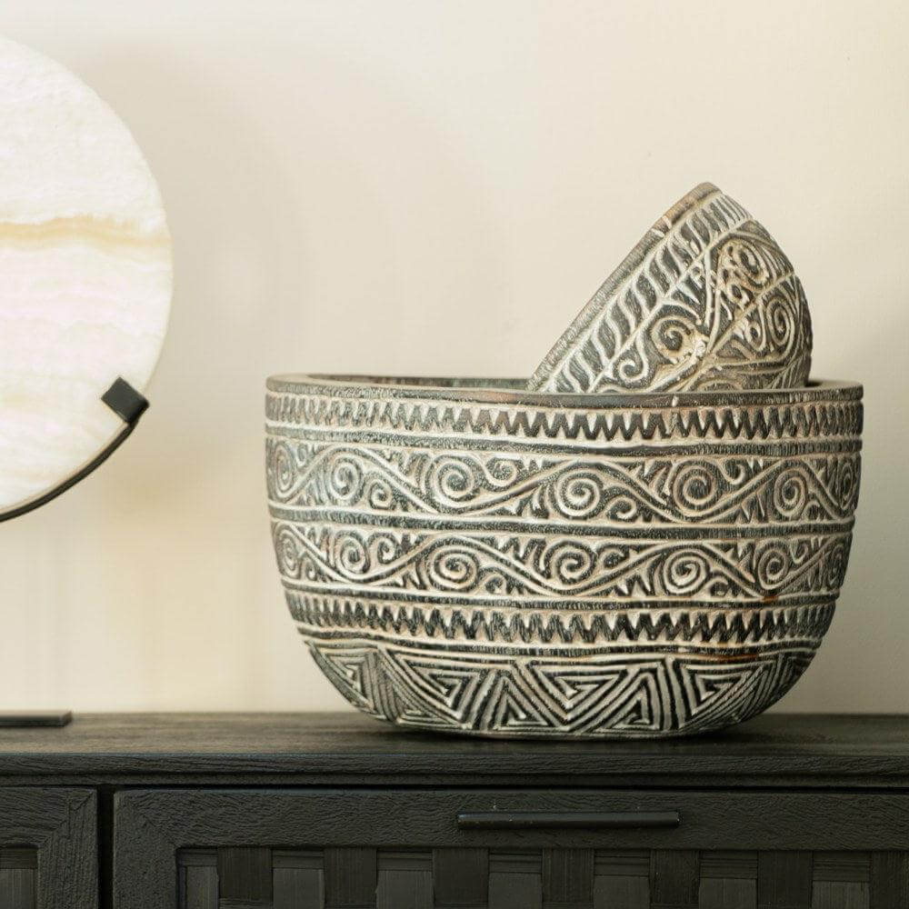 Decoratieve schaal Keoni met etnische patronen, geplaatst op een donkere kast naast een stijlvolle lamp. Perfect voor een exotisch interieur.