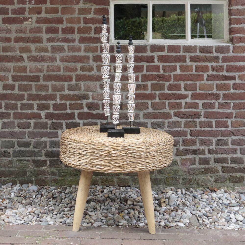 Schelpenstick Yoko op rustiek tuinmeubel tegen een bakstenen muur, boho interieurdecoratie met natuurlijke schelpen en ambachtelijk ontwerp.