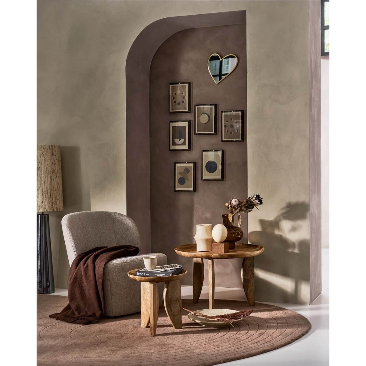 Bohemian-style room with a heart-shaped gold mirror from vtwonen, featuring cozy chairs and wooden tables on a round rug.
