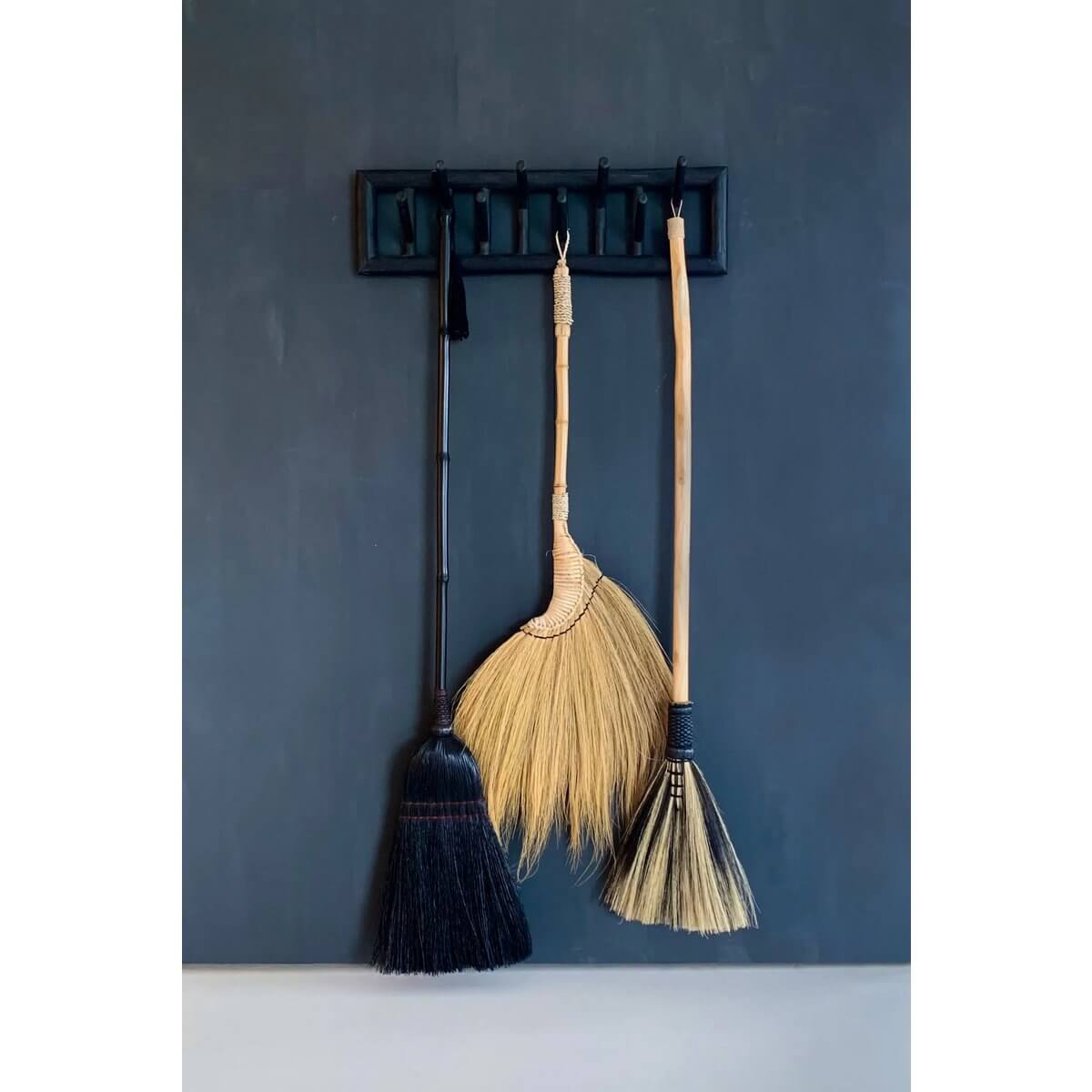 Trio of bohemian brooms hanging on a wall; The Big Broom in zwart made of grass and wood for decor. Perfect for indoor or covered outdoor spaces.