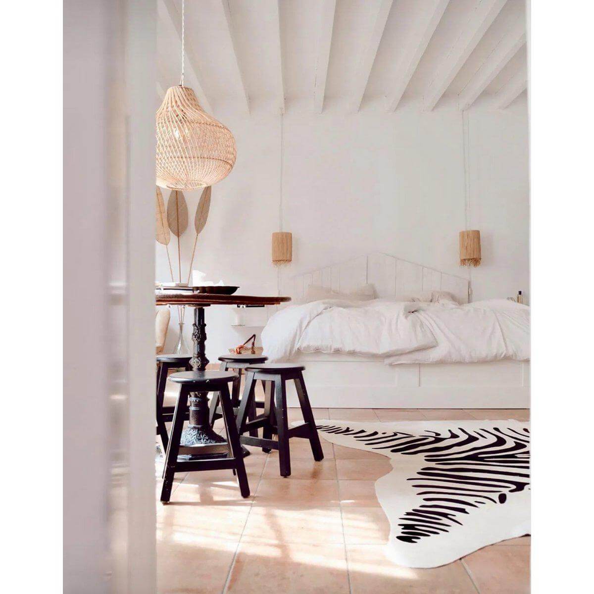 Boho slaapkamer met rotan hanglamp, rustieke meubels en zebra vloerkleed. Stijlvolle en natuurlijke inrichting met "The Bottle Hanger - Naturel".