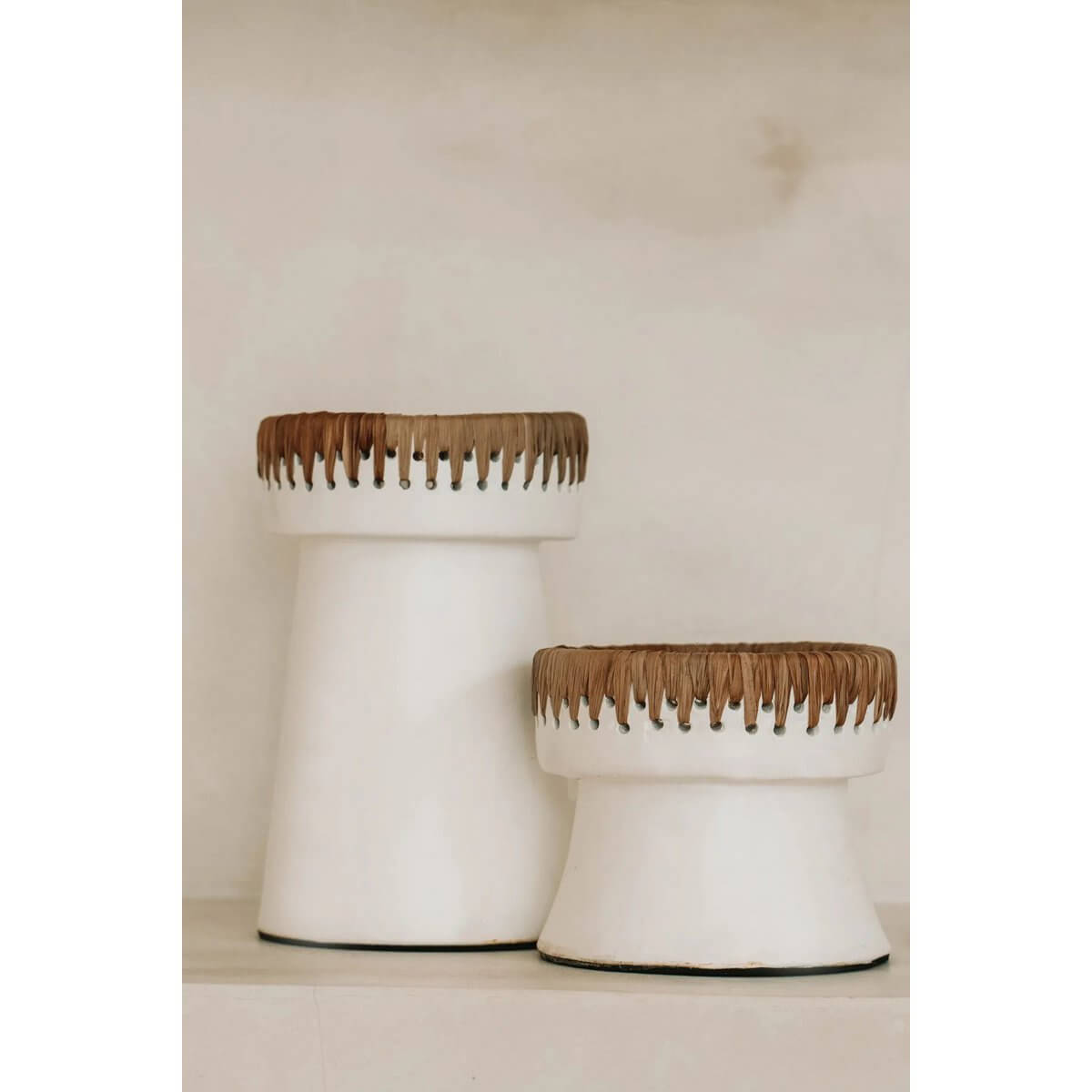 Bohemian style white terracotta candle holders with raffia accents, perfect for adding elegance to any decor.