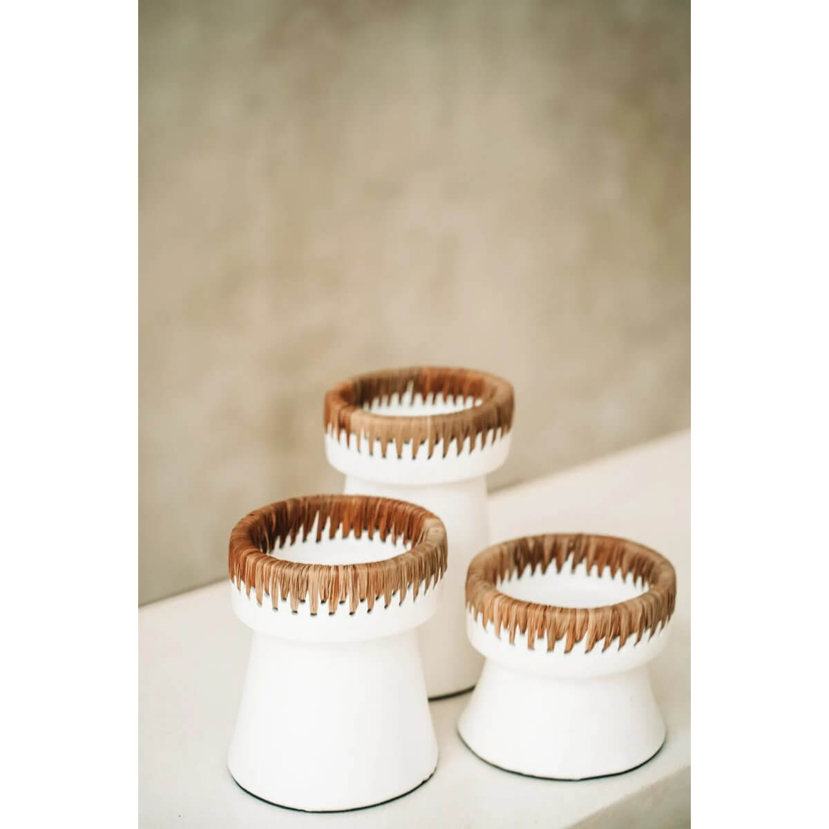 Three white terracotta candle holders with raffia accents, perfect for a bohemian decor style table display in varying heights.