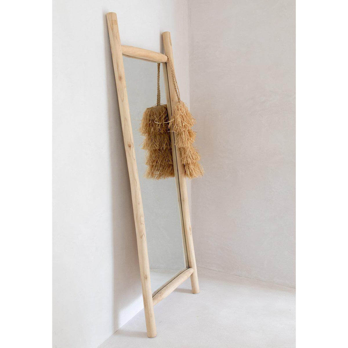 Alt Tag: Spiegel met raffia tas in natuurlijke setting, straalt strandvibes uit.
