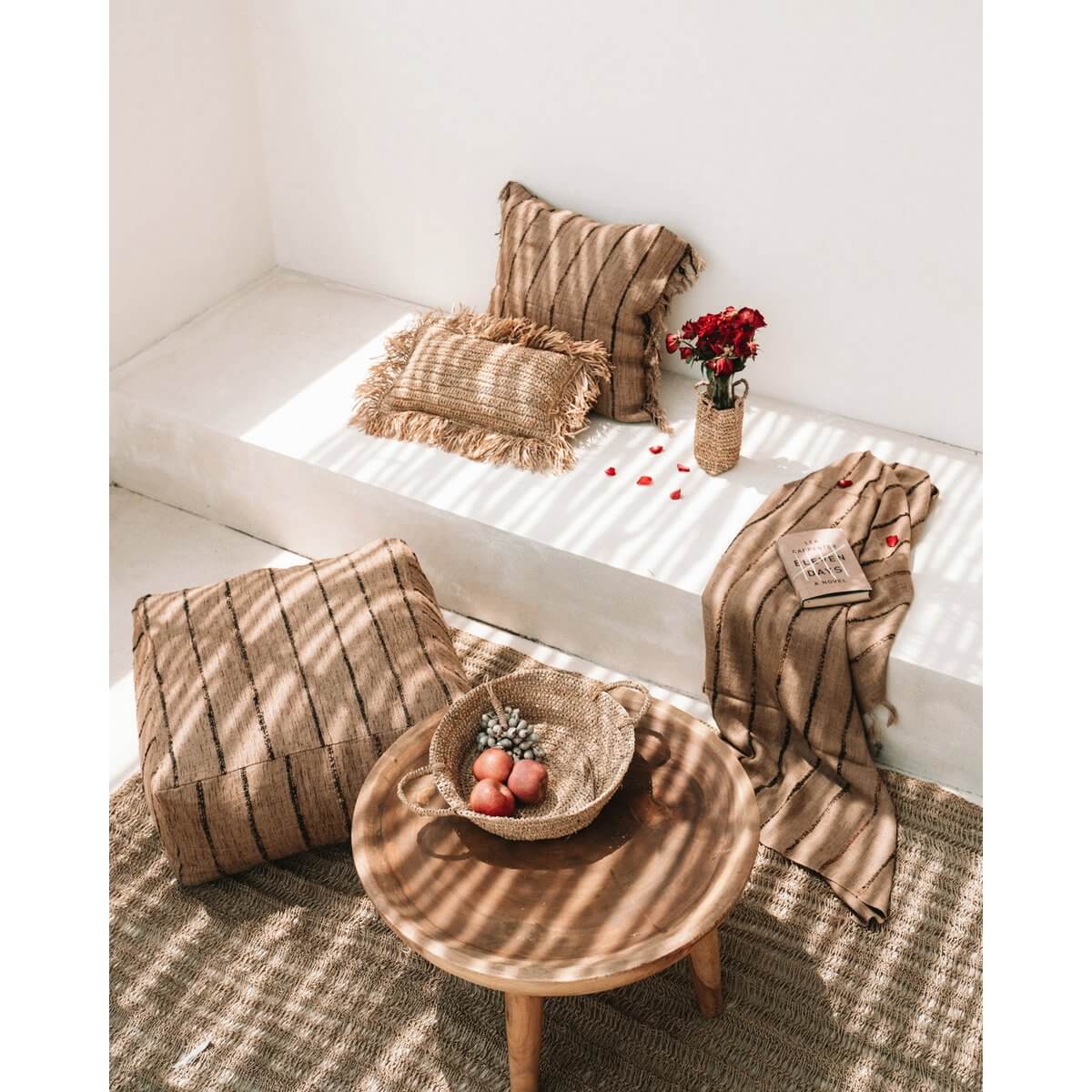 Bohemian decor with Raffia Basket Tray filled with fruit, cozy pillows, and throws on a bench, creating a rustic and elegant ambiance.