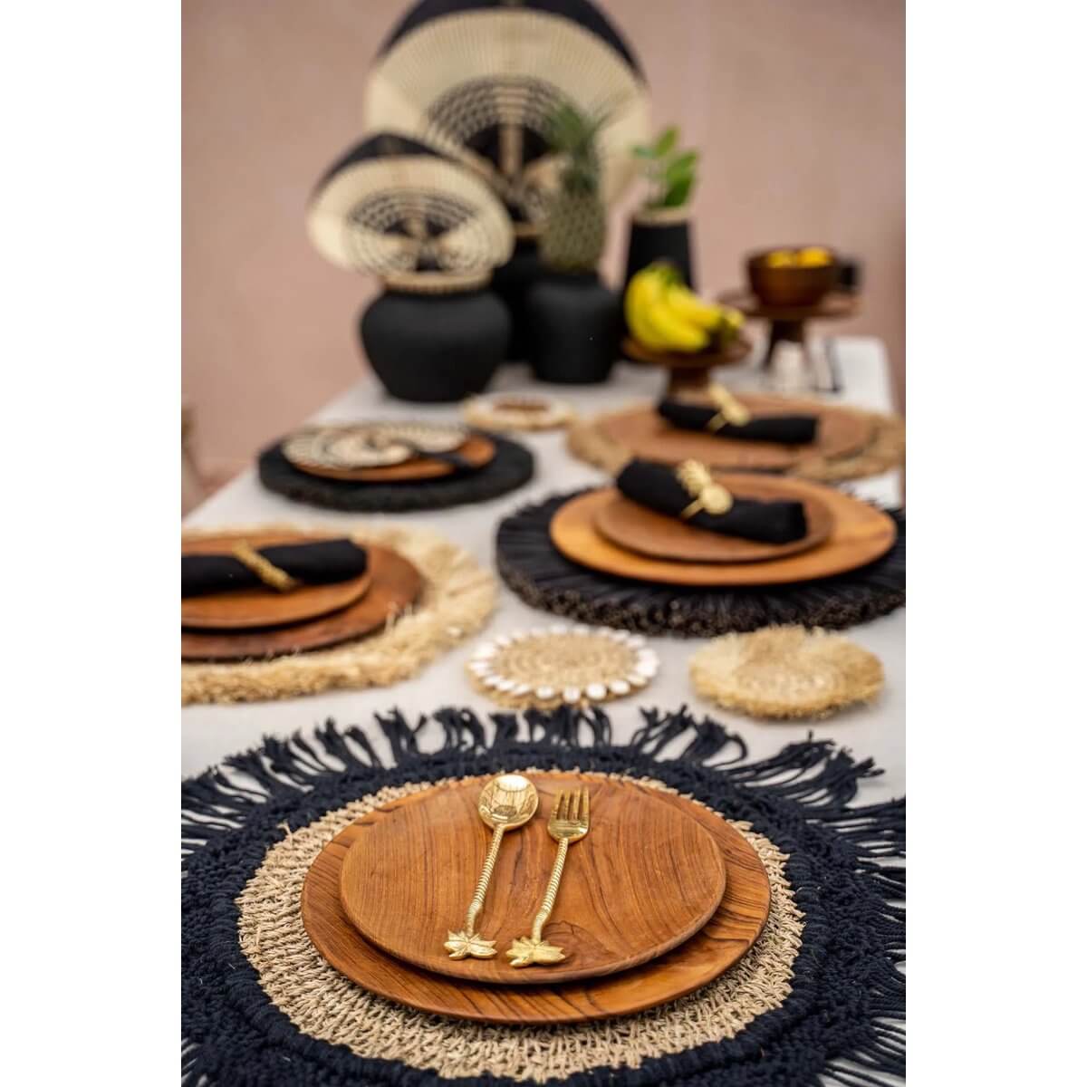 Bohemian-style table setting with Teak Root Round Plates, layered placemats, and gold cutlery, adding a warm wooden touch to the decor.