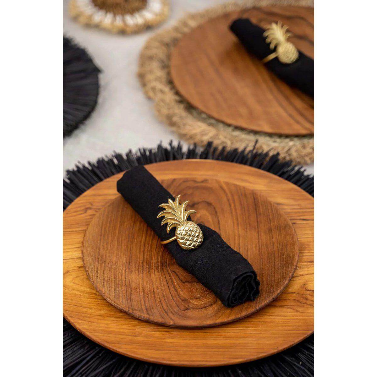 Teakhouten rond bord met zwarte servet en gouden ananas servetring, Bazar Bizar Living, stijlvolle tafeldecoratie