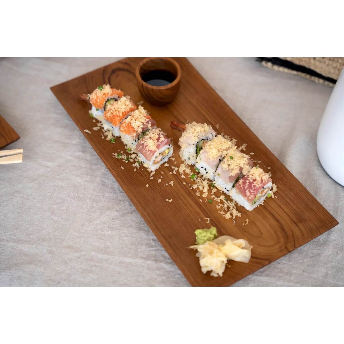Bohemian teak root sushi plate displaying vibrant sushi rolls, with soy sauce cup, on a rustic brown wooden board. Perfect for stylish dining.