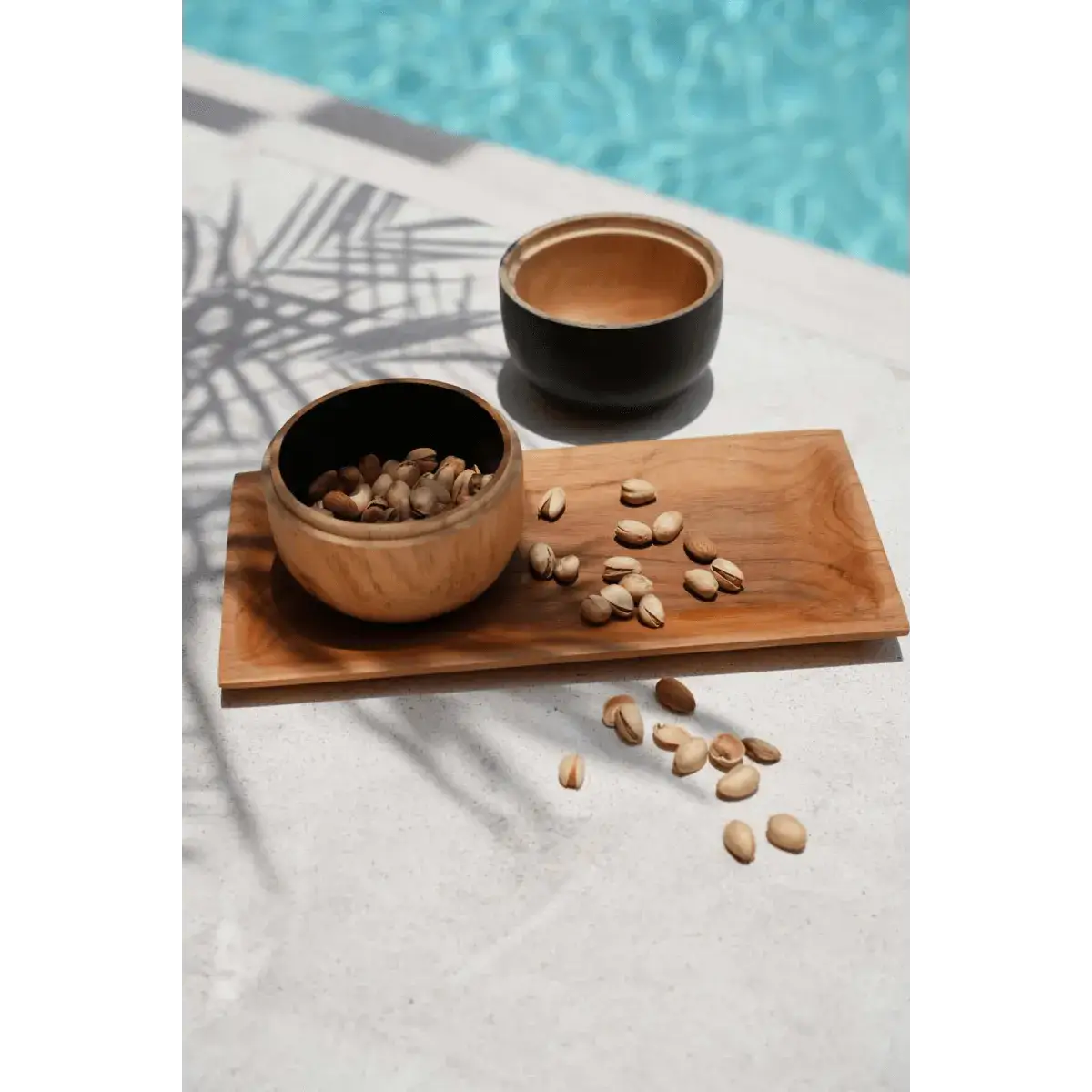 Bohemian teak root sushi plate with bowls by a pool, showcasing elegance and versatility in outdoor dining.