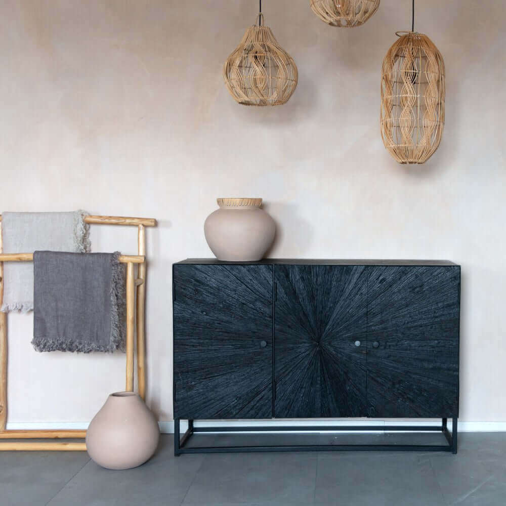 Bohemian interieur met terracotta vaas, rotan lampen en zwarte kast. Authentieke sfeer voor een stijlvolle woonkamer.