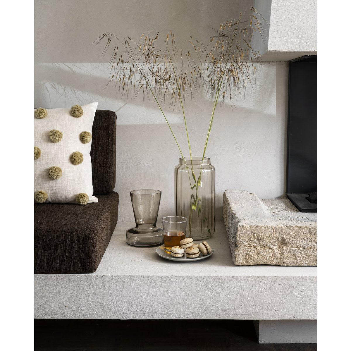 Stijlvolle woonkamerdecoratie met vtwonen vaas, glas en macarons op een witte plank.