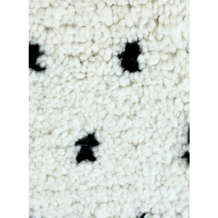 Dichtbij opname van Beni Ouarain kussen met gestikte zwarte stippen en witte achtergrond - perfect voor modern interieur.
