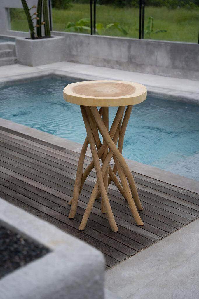 De Gili Bartafel naast een zwembad, met verweven teakhouten takken en een stevige bovenkant, perfect voor een tropische eiland sfeer.