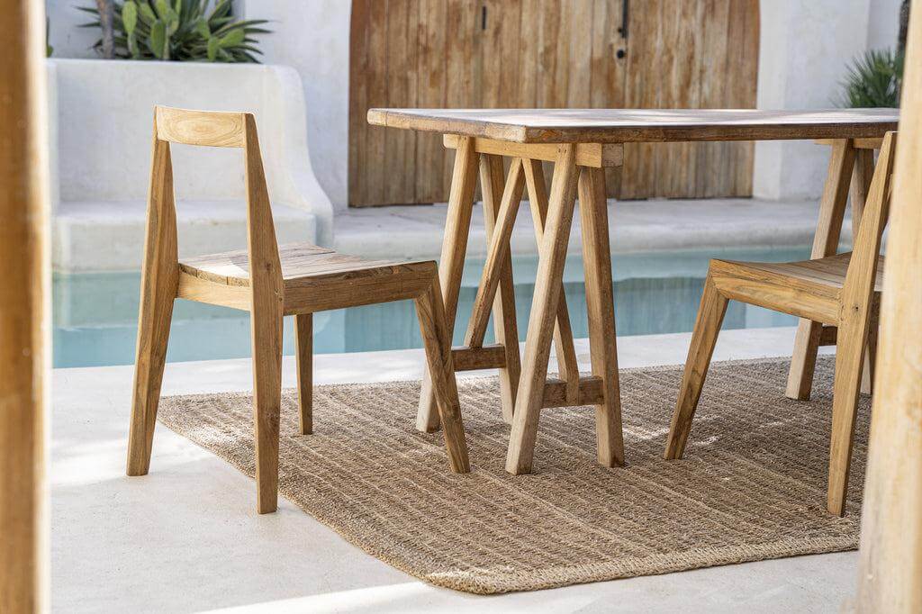 Handgemaakte De Paxi Stoel van reclaimed teakhout voor buitengebruik, elegant naast zwembad op een zonnig terras.