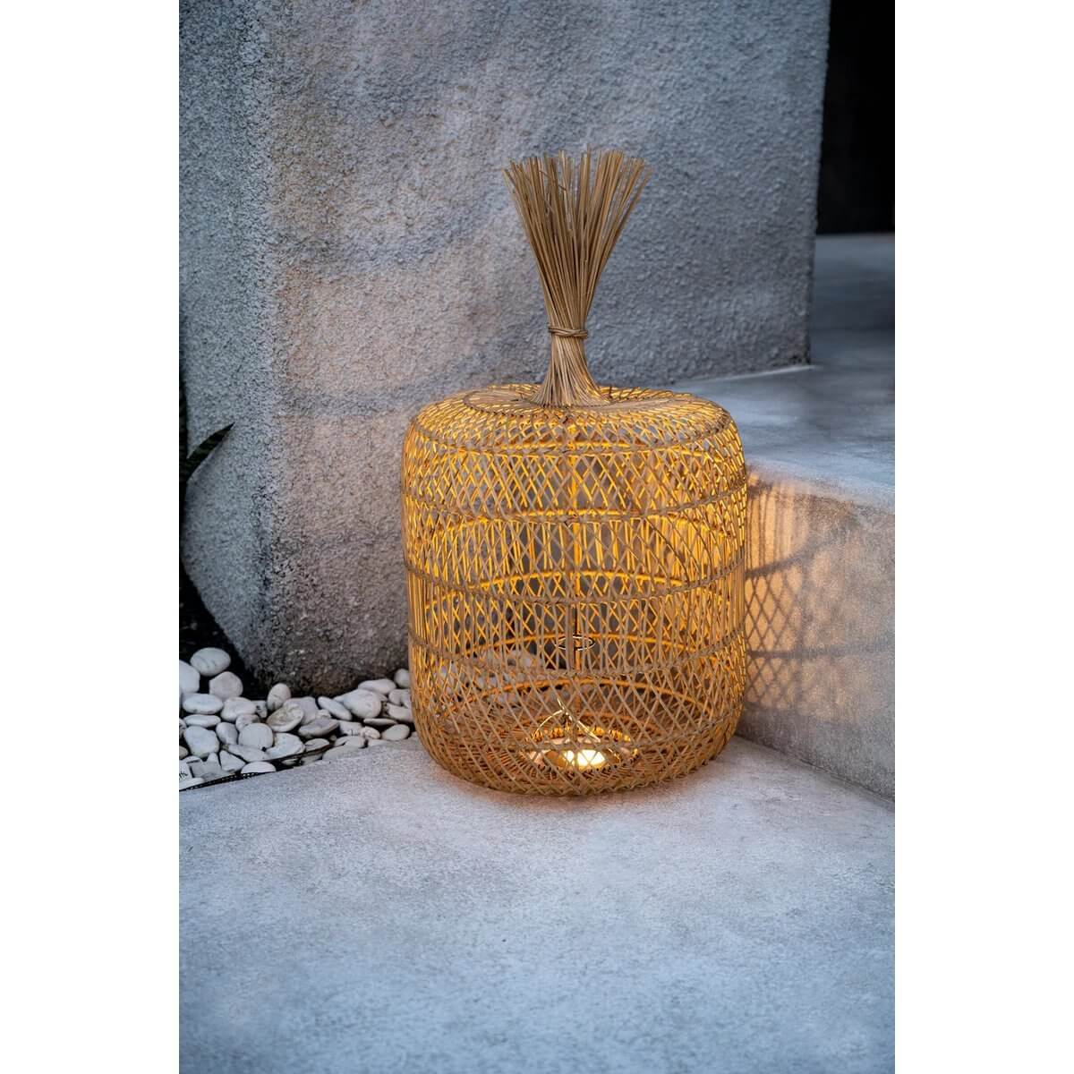 Rotan Dumpling vloerlamp in boho-stijl verlicht een betonnen hoek, ideaal voor gezellige interieurs.