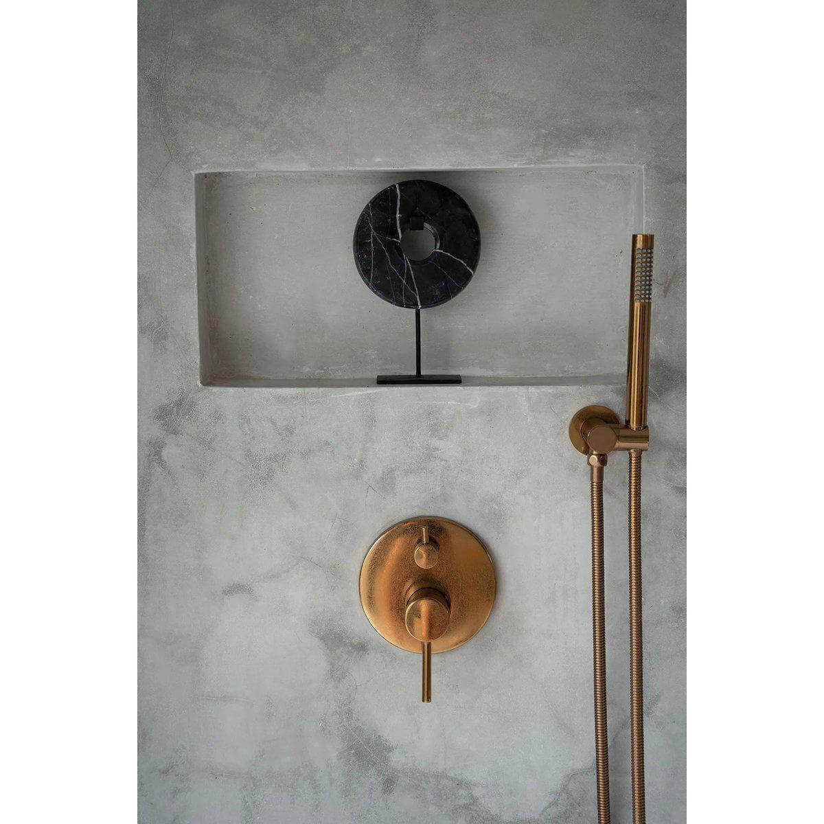 Zwarte marmeren schijf op standaard tegen minimalistische muur met metalen douchekop, strakke en stijlvolle interieurdecoratie.