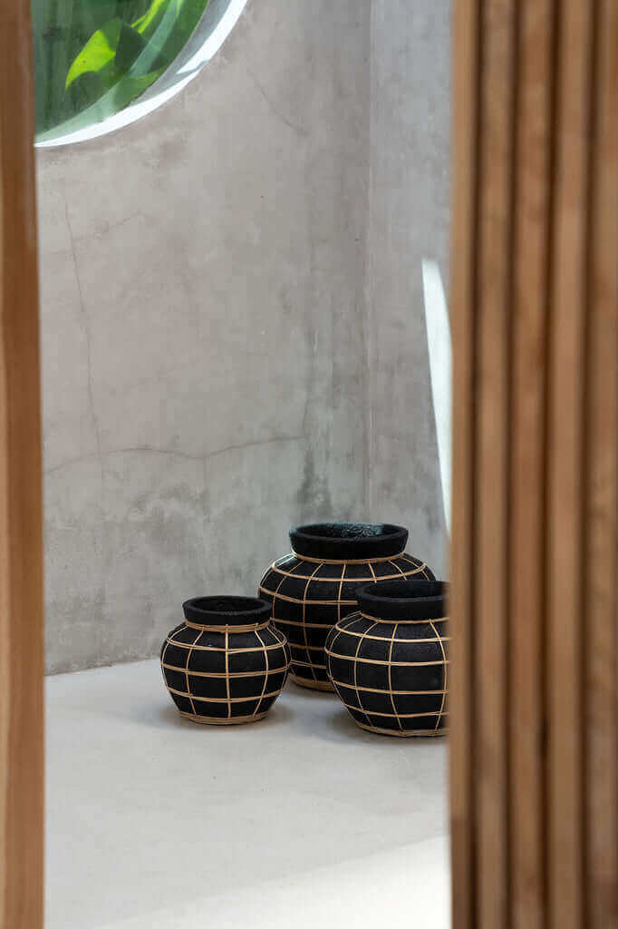 Drie De Belly Vazen in zwart en naturel met rotan detail, perfect voor droogbloemen. Gemaakt van terracotta voor een kustvibe.