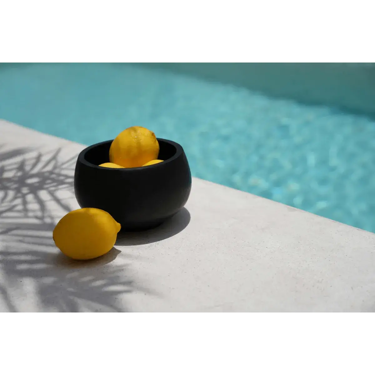 Bohemian De Bondi Black Bowl holding lemons by a pool, showcasing multifunctional style and elegance.