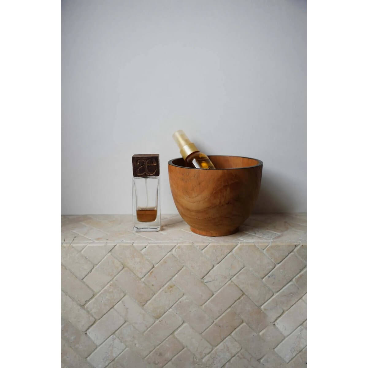 Bohemian-style teak candy bowl perfect for makeup or snacks, alongside a perfume bottle on a tiled surface.