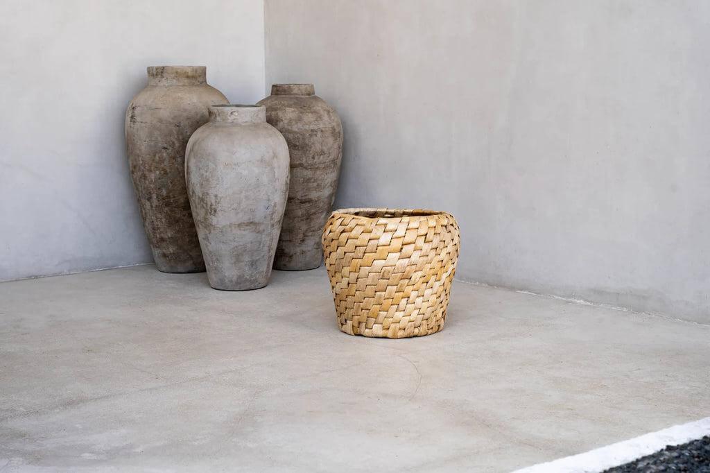 Chidi mand van licht bananenblad met diagonaal patroon, naast rustieke vazen. Perfecte mix van stijl en functionaliteit in natuurlijke kleuren.
