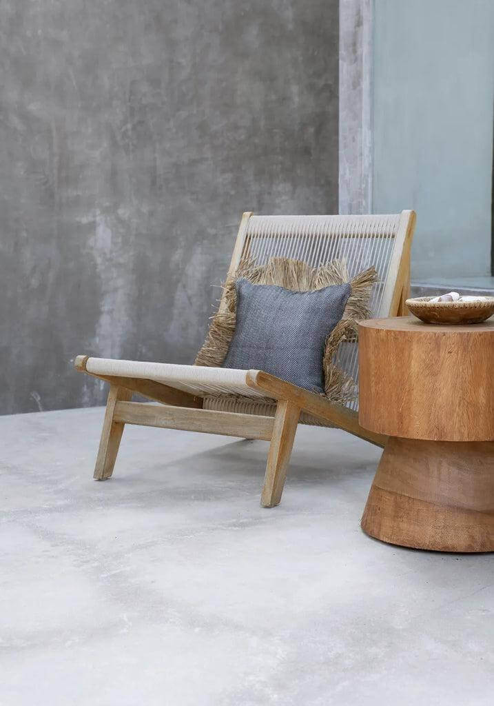 Scandinavische fauteuil met kussenhoes in zwart-wit en raffia franjes, perfecte zomervibes voor binnen of buiten. De Cotton Bonita 40x40