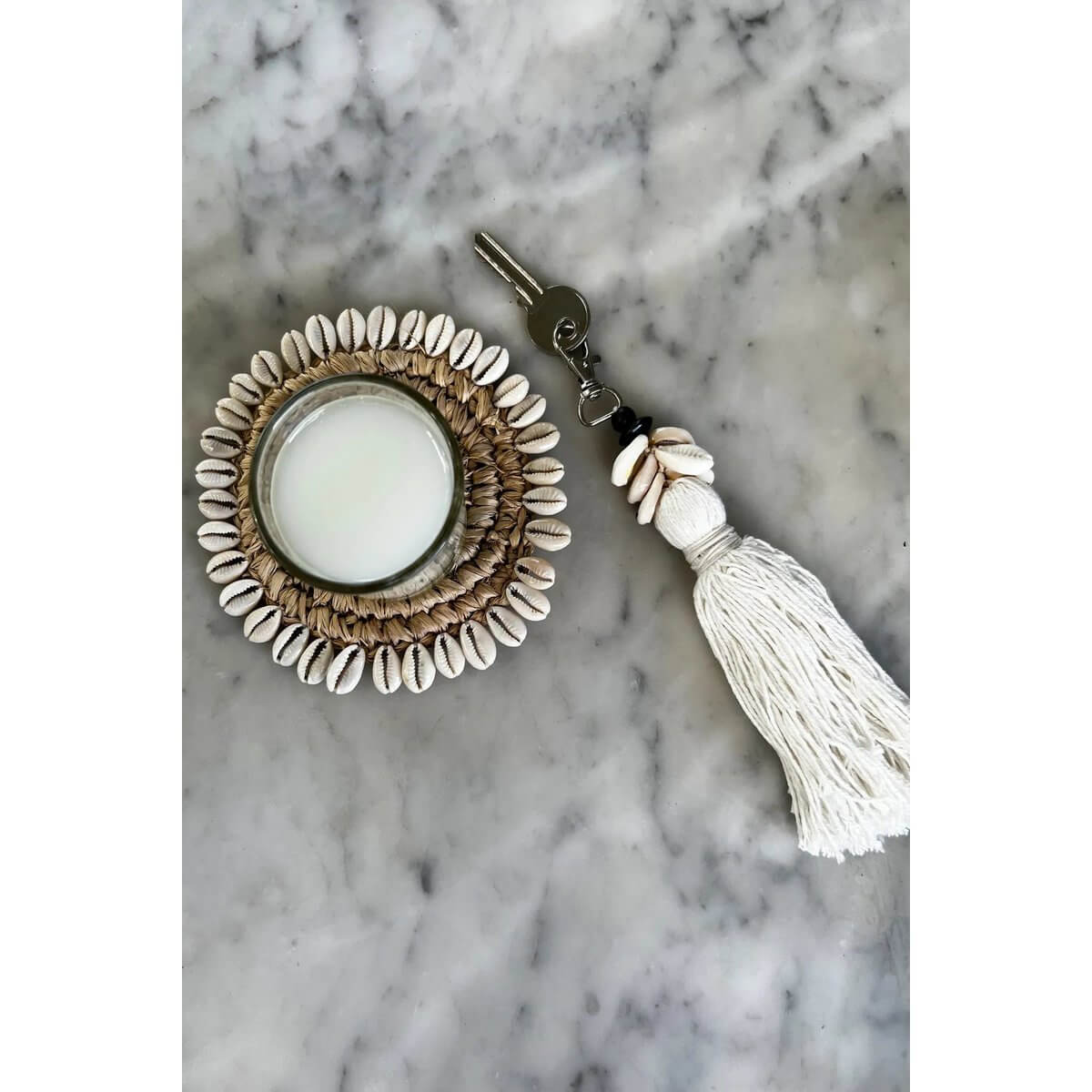 Bohemian De Cowrie Tassel Keychain with shells and cotton tassel, perfect for home styling or gifting, displayed on marble surface.