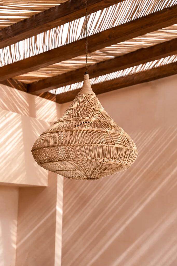 De Drop Hanglamp Naturel van rotan in druppelvorm, hangend onder een houten plafond, sfeervolle verlichting voor elk interieur.