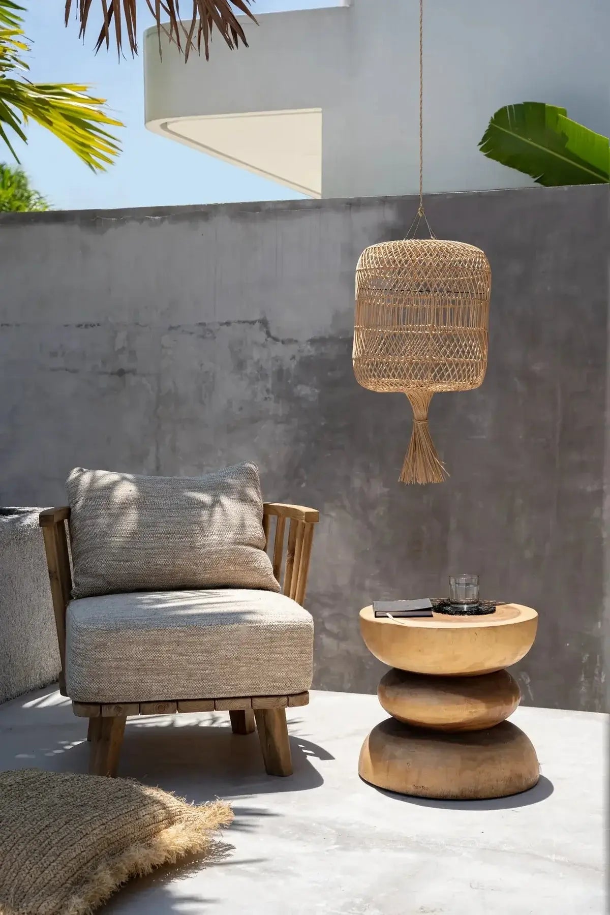Boho buitenruimte met natuurlijke rotan hanglamp, houten bijzettafel en loungestoel; stijlvolle uitstraling voor je tuin.