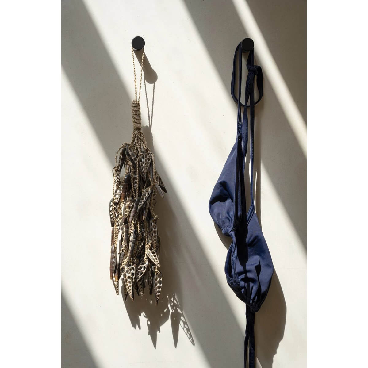Bohemian style brown shell tassel hanging on wall with shadows, perfect as a decorative piece or keychain, next to a blue item.