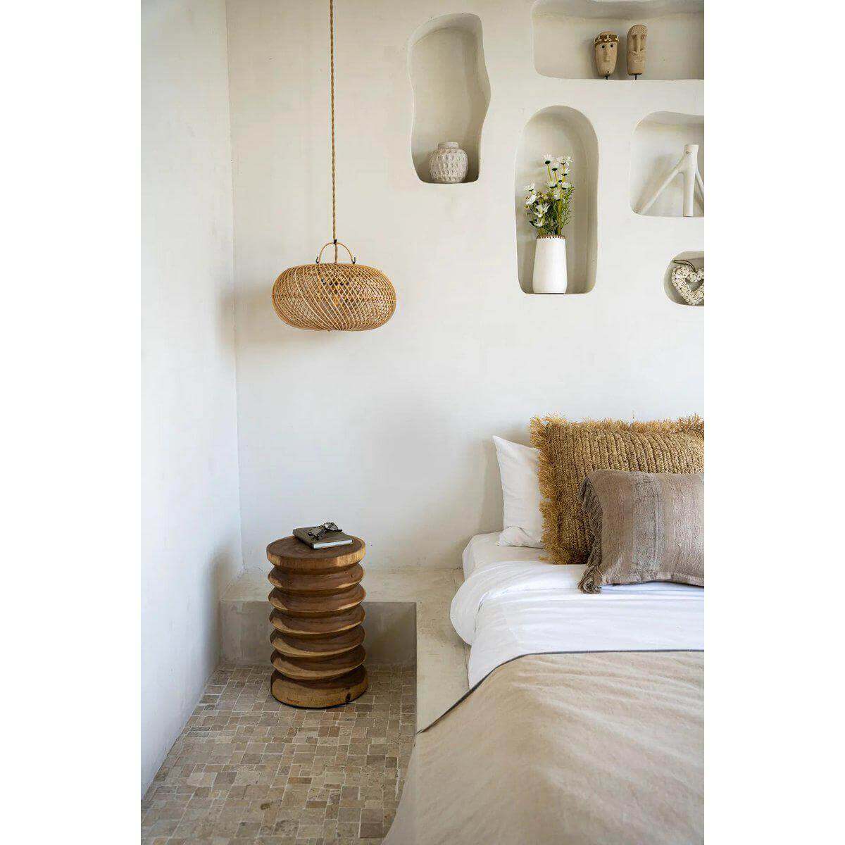 Stijlvolle slaapkamer met de Galapagos kruk in natuurlijke tinten, houten en rieten decor tegen een rustieke muur.